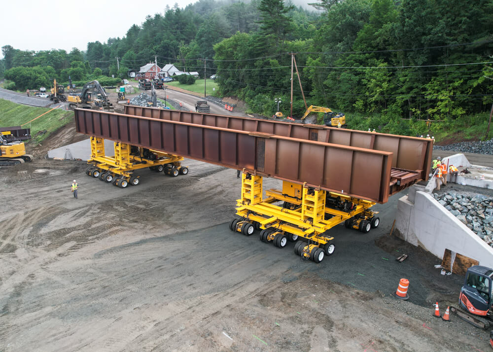 Metal railway bridge section on two yellow dolly transporters